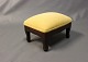 Small footstool in polished mahogany and bright yellow fabric.5000m2 showroom.